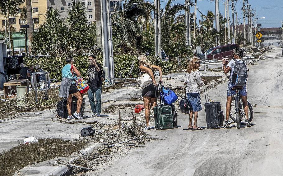Residents walk along Estero Boulevard with suitcases as they leave the Fort Myers Beach Island on Friday September 30, 2022, two days after Hurricane Ian hit Florida’s west coast as a Category 4 storm.
