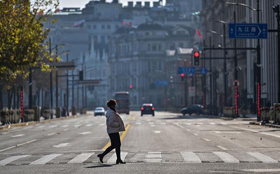 A woman crosses a street on the Bund in the Huangpu district in Shanghai on Dec. 21, 2022. 