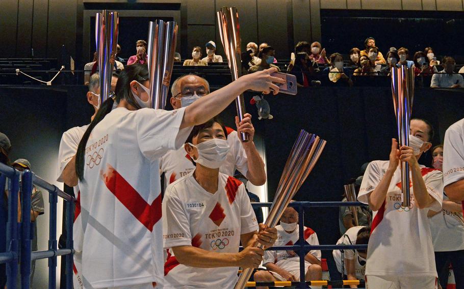 Tokyo Olympics torch relay runners take a selfie during an indoor ceremony in Tachikawa, Japan, Monday, July 12, 2021.