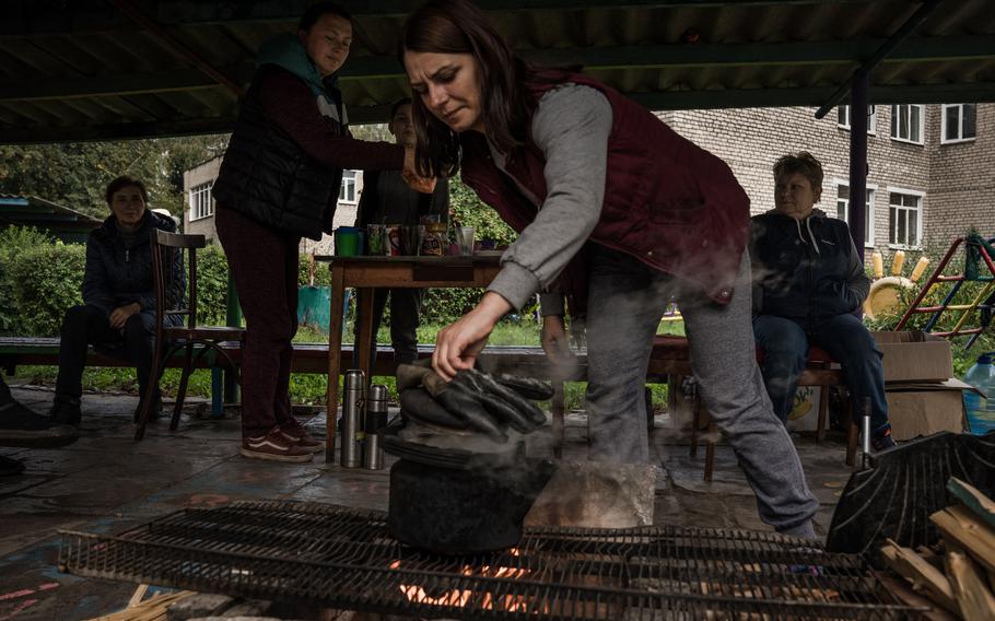 Anna Kobets heats water for tea and coffee outside the kindergarten where she has lived with others in Izyum since the war began.