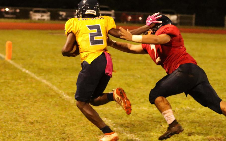 Guam High's Benjamin Harris stiff-arms past Okkodo defender Fermancio Jay Garcia.