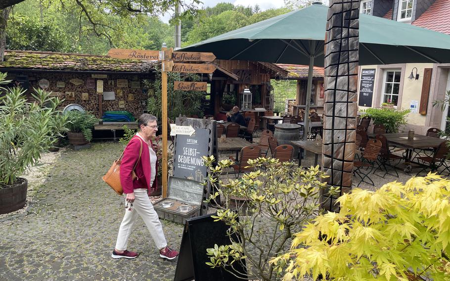 A woman walks in a cafe’s outdoor dining area.