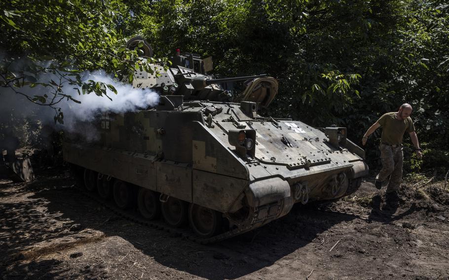 A soldier from Ukraine’s 47th Mechanized Brigade runs past a U.S.-made Bradley Fighting Vehicle as the engine is started at a secret workshop in a wooded area in the Zaporizhzhia region in July. 