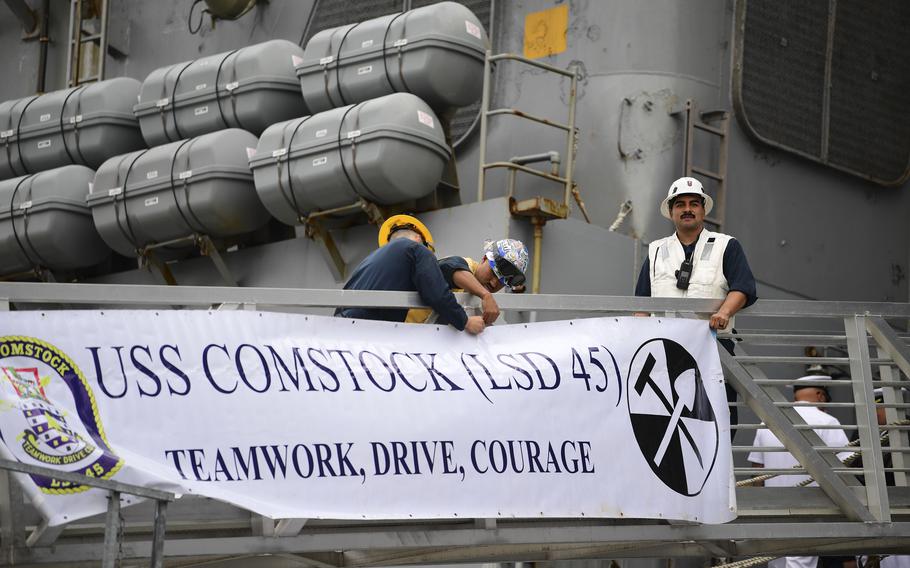 Sailors hang a USS Comstock banner on the brow of the ship
