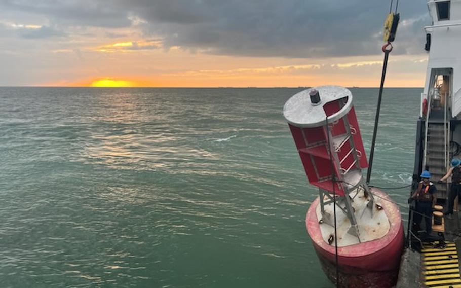 A red buoy is seen near the side of a ship, with water taking up most of the photo’s space.