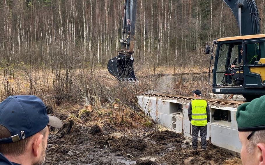 Lithuanian military and law enforcement personnel observe efforts to recover a U.S. Army armored vehicle.