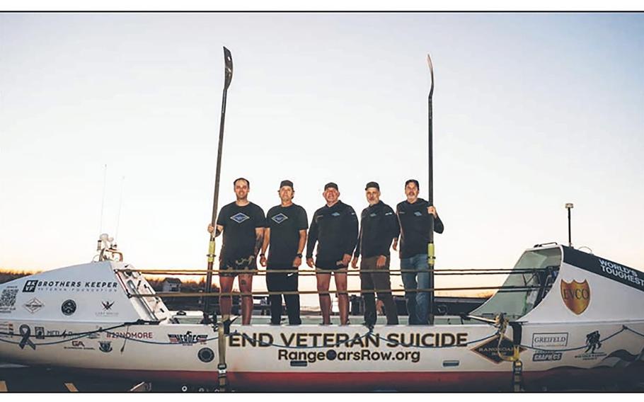 Five men stand on a boat together holding up paddles