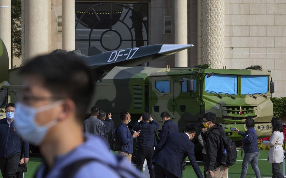 Visitors look at a Chinese military vehicles carrying DF-17 ballistic missiles on Wednesday, Oct. 12, 2022. 