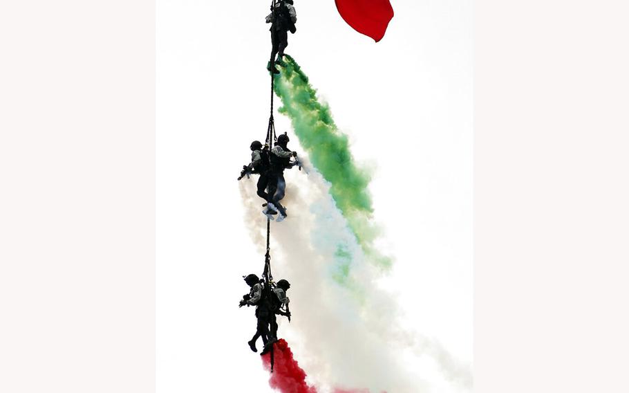 Special forces hang from a helicopter with billowing smoke in the colors of the Mexican flag during the annual Independence Day military parade at the main square, the Zocalo, in Mexico City, Friday, Sept. 16, 2022.
