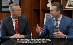 Doug Collins watching Pete Hegseth talk, with Hegseth gesturing.