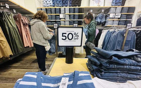 Women shop in a Gap store. A sign between them says 50% off.