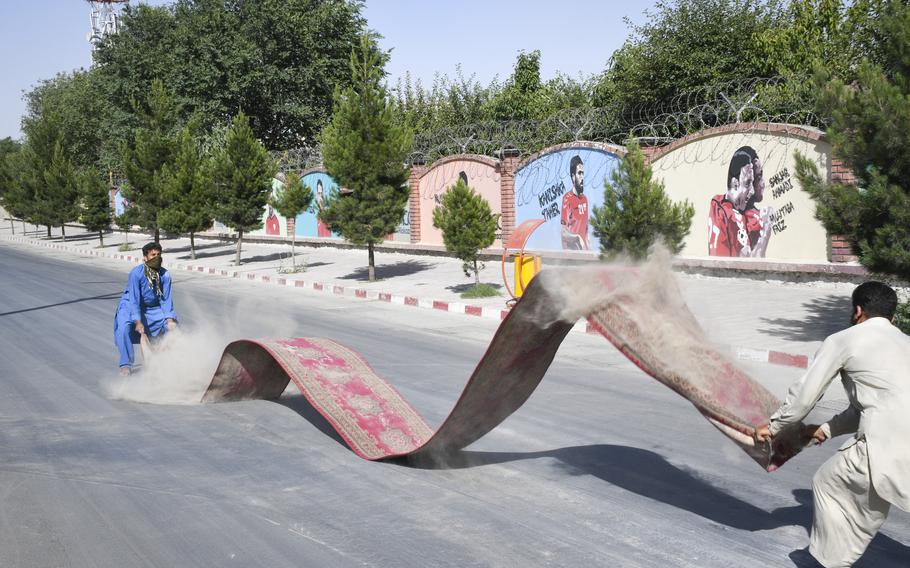 Aftaab, 21, a shopkeeper wearing blue clothing, shakes thick clouds of dust from rugs ruined after a bombing claimed by the Taliban on July 1, 2019, collapsed several buildings at the nearby Watan Furniture Market. The blast shook the ground like an earthquake, Aftaab said. 