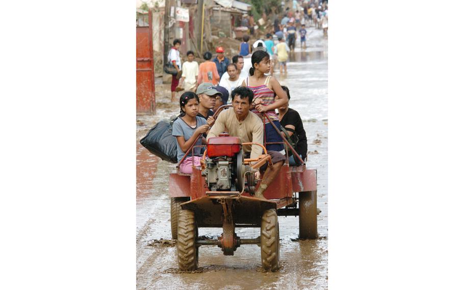 People in the town of Infanta avoid flood waters in improvised vehicles such as this tractor, beside a distribution point for U.S. Marines delivering aid in the country.