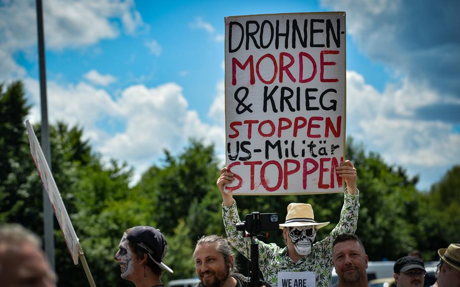 A protester holds a sign calling for an end of drone killings, war and U.S. military activity at a “Dance of the Dead” protest in Ramstein-Miesenbach, Germany, June 25, 2022. 