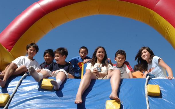 Children peer over a photographer from atop a bouncy castle.
