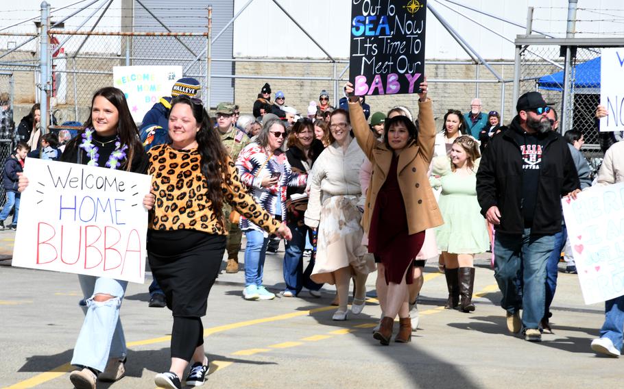 Families carry signs on the pier.