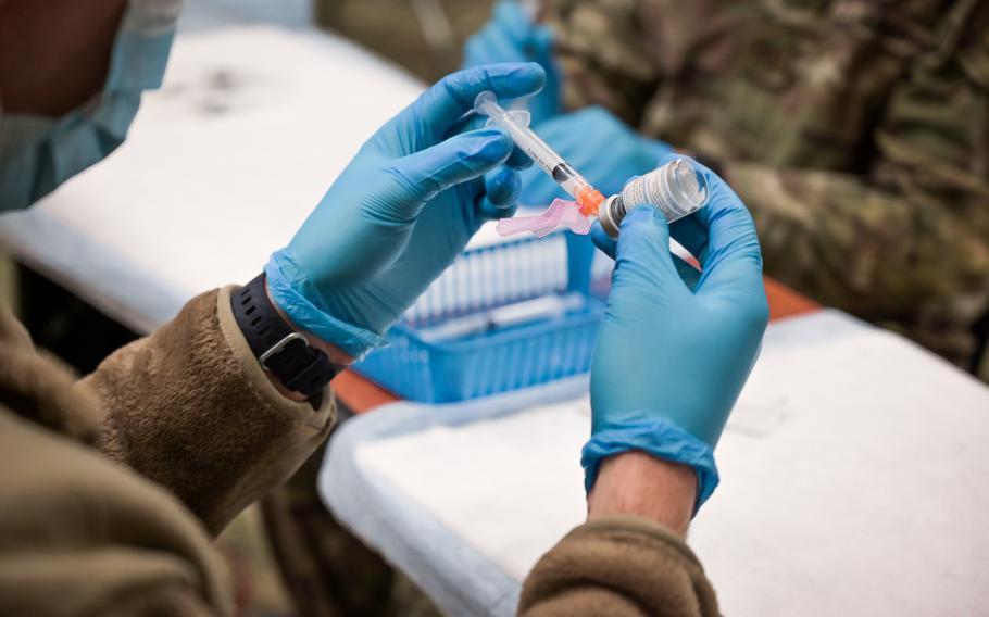 A U.S. Army combat medic draws the COVID-19 vaccine into a syringe.