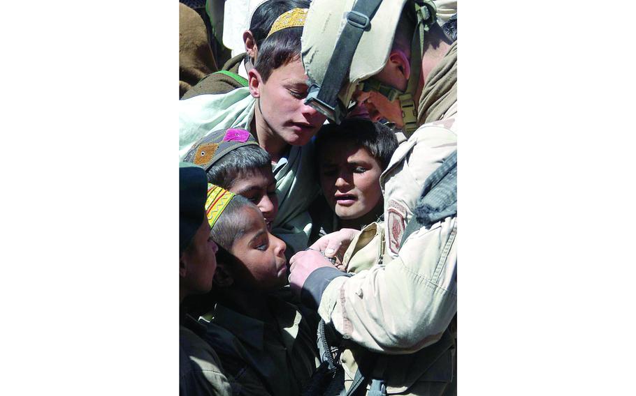 Spc. Jesse Davis, of the 1st Platoon, Company A, 1st Battalion, 508th Infantry Regiment, shows boys in Naka, Afghanistan, their pictures after taking them with a digital camera during a patrol through the town.