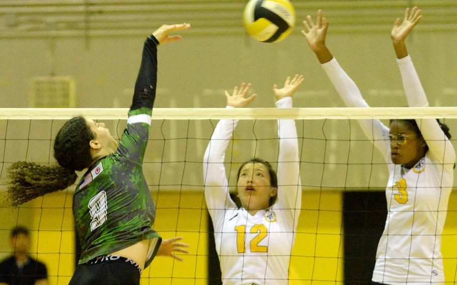 Kubasaki's Olivia Schaffeld spikes between the double block of Kadena's Christina Kehe and Liza Young during Tuesday's Okinawa volleyball matach. The Dragons won in five sets to level the season series 1-1.