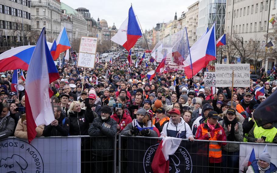 People wave flags and banners as they gather to protest against the government’s restrictions to curb the spread of COVID-19 in Prague, Czech Republic, Sunday, Jan. 9, 2022.