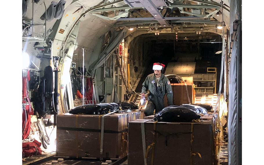 Senior Airman Walter Frank makes a final check of the Operation Christmas Drop donation boxes before a flight over the Northern Mariana Islands, Dec. 9, 2018. The black bags atop the boxes contain parachutes.