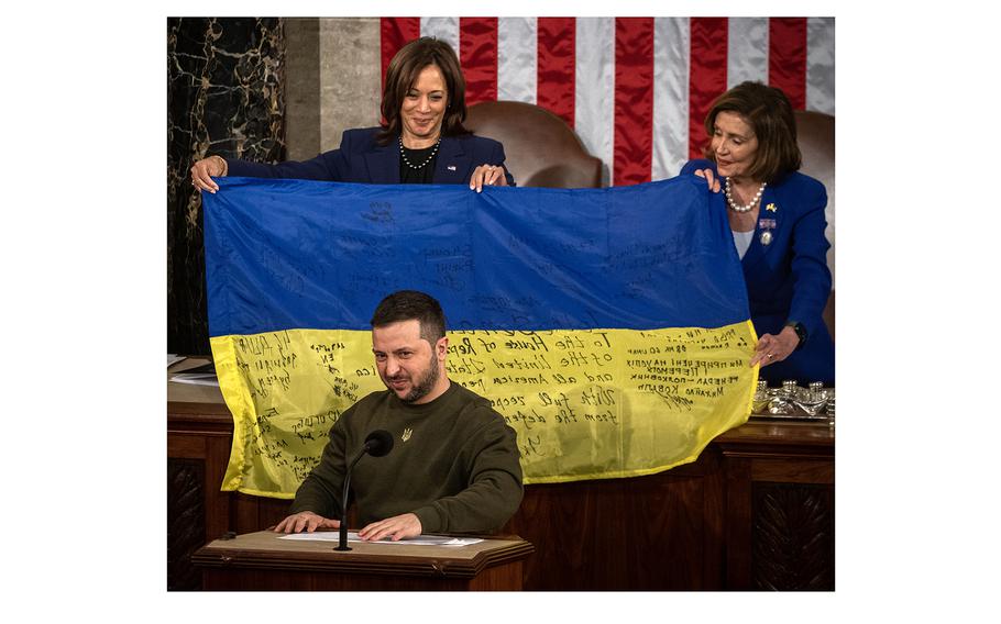 Ukrainian President Volodymyr Zelenskyy stands before a Ukrainian flag held up by Vice President Kamala Harris and then-House Speaker Nancy Pelosi.