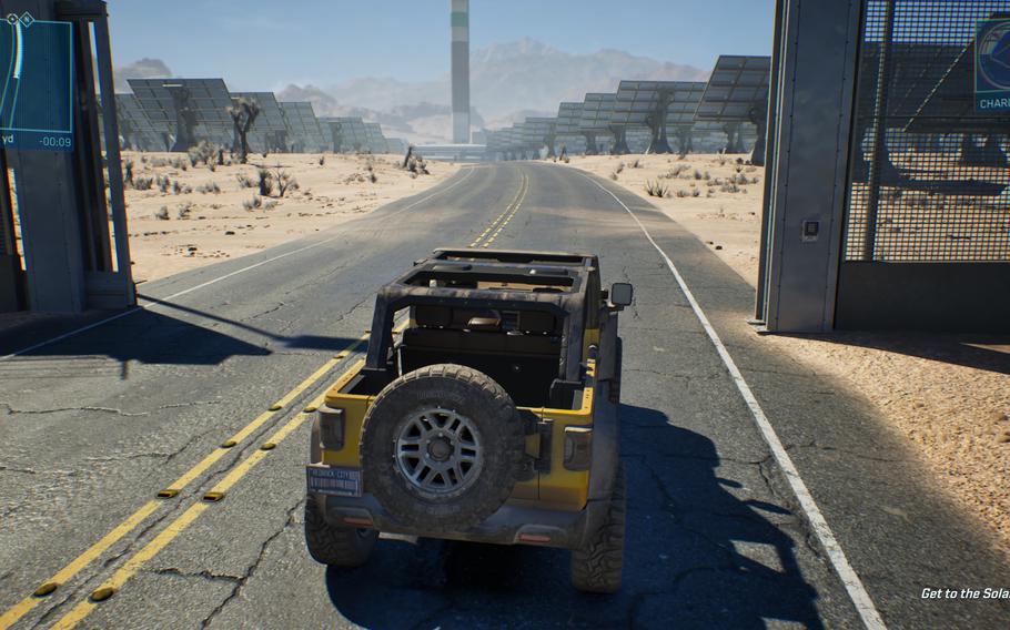 A jeep in a video game drives down a dusty road toward an open security gate.