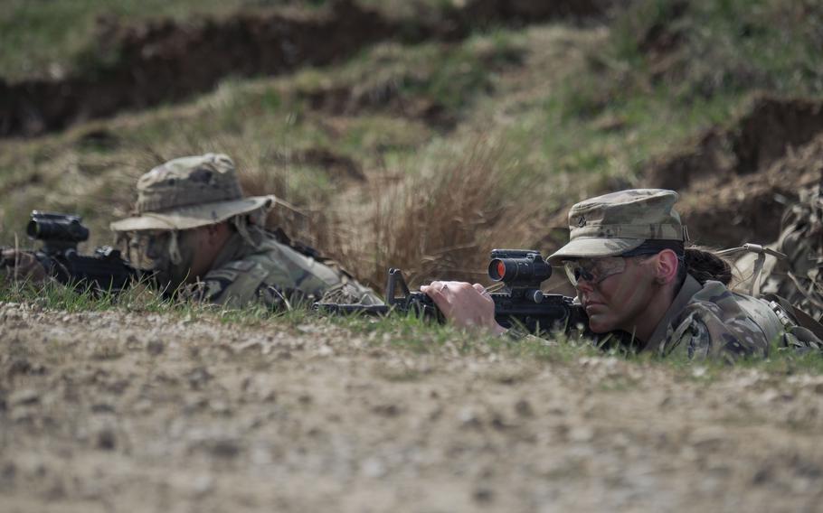 Two US Army soldiers using binoculars to see the field. 