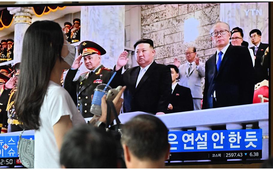 A woman walks past a television screen showing a news broadcast with an image of North Korean leader Kim Jong Un attending a military parade held in Pyongyang to mark the 70th anniversary of the Korean War armistice, at a railway station in Seoul on July 28, 2023. 