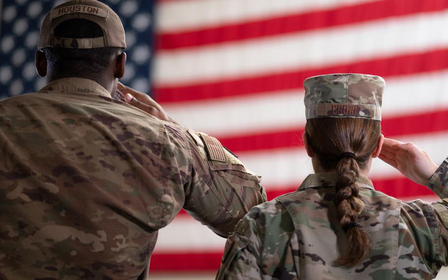 Two service members salute the flag