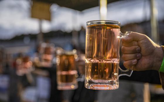 A hand holds a glass of beer.
