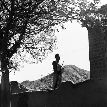 A man with a bayonet stands guard on a wall or fort.