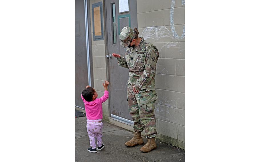 A young girl waves at a soldier outside an Operation Allies Welcome community building Thursday, Oct. 14, 2021, at Camp Atterbury in Edinburgh, Ind.