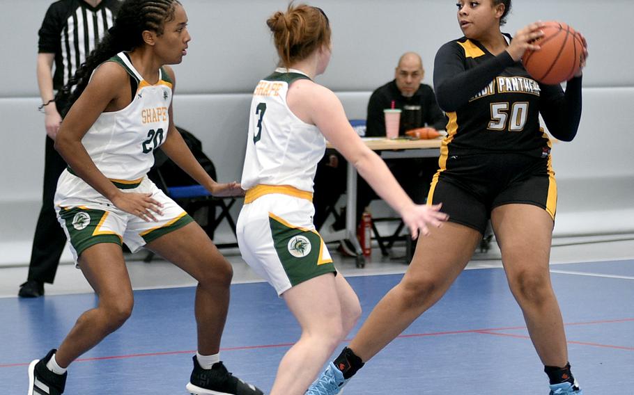 Stuttgart's Icsiss Perez looks to pass as SHAPE's Addie Atkins and Macy Gilbert defend during pool play of the Division I DODEA European Basketball Championships on Wednesday at Ramstein High School on Ramstein Air Base, Germany.