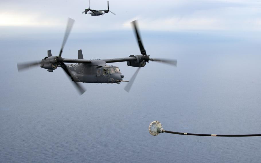 An Osprey in the foreground flies near a MC-130J Commando II for refueling as another Osprey flies in the background.