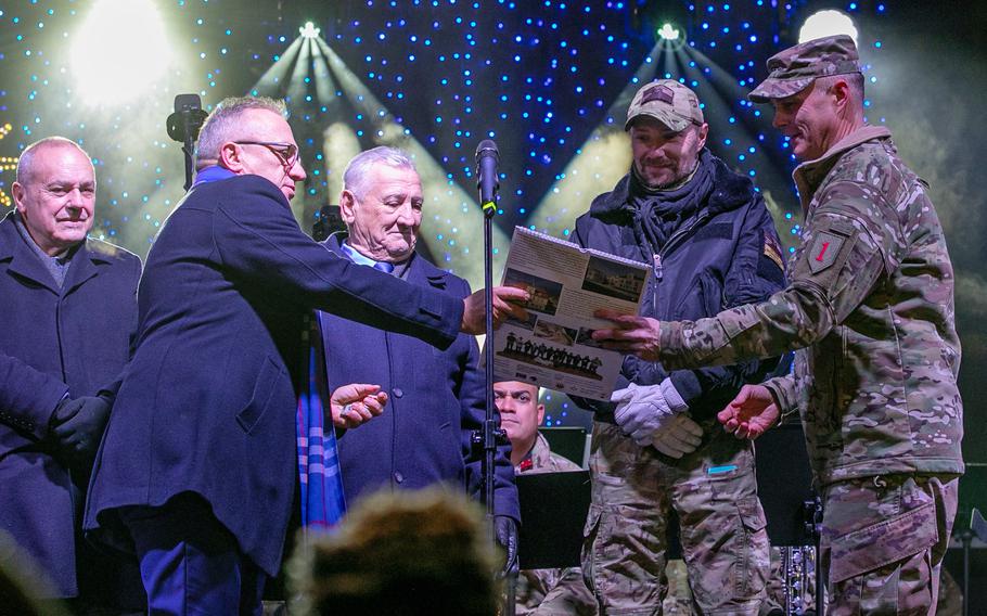 Army Maj. Gen. John Meyer III, commanding general of the 1st Infantry Division, receives a gift from Piotr Roman, the mayor of Boleslawiec, Poland, during a band concert in the military town Dec. 16, 2022.