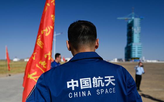 A staff member stands before a Long March-2F carrier rocket, carrying the Shenzhou-17 spacecraft, on the launch pad encased in a shield at the Jiuquan Satellite Launch Centre in the Gobi desert in northwest China on Oct. 25, 2023. (Pedro Pardo/AFP via Getty Images/TNS)