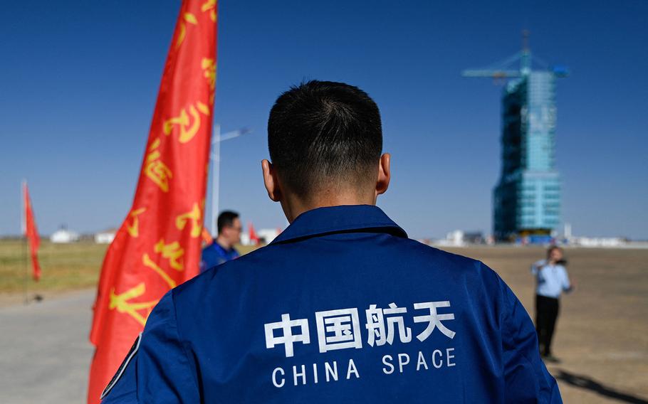 A staff member stands before a Long March-2F carrier rocket, carrying the Shenzhou-17 spacecraft, on the launch pad encased in a shield at the Jiuquan Satellite Launch Centre in the Gobi desert in northwest China on Oct. 25, 2023.