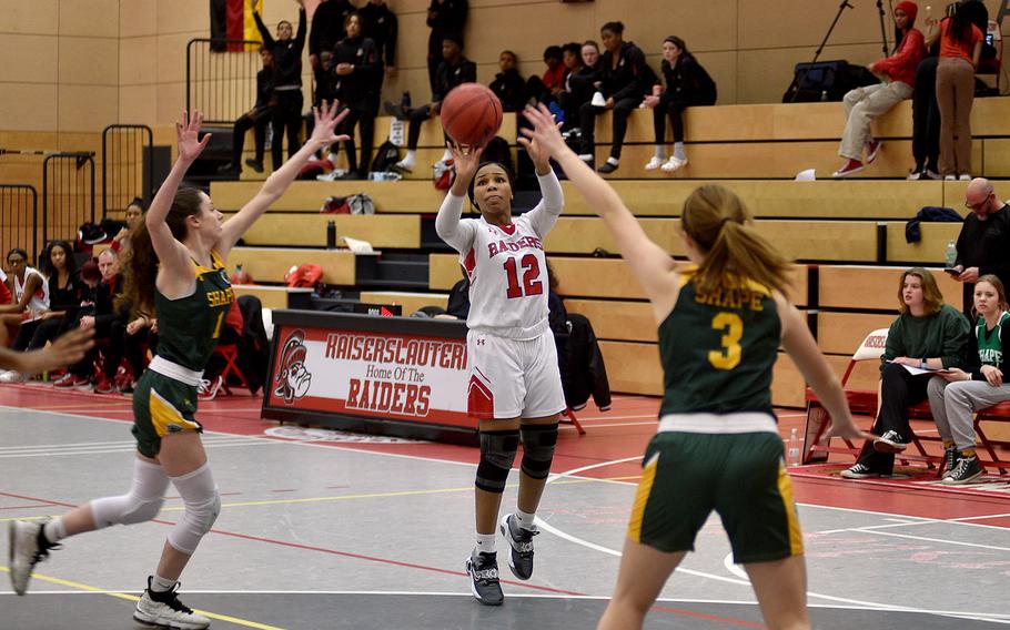 Kaiserslauterns Se'maiya Farrow schießt, während Jessica Moon und Macy Gilbert von SHAPE während des Spiels am Freitagabend in der Kaiserslautern High School in Kaiserslautern, Deutschland, verteidigen.  Die Raiders schlugen die Spartans in der Verlängerung mit 43-41.