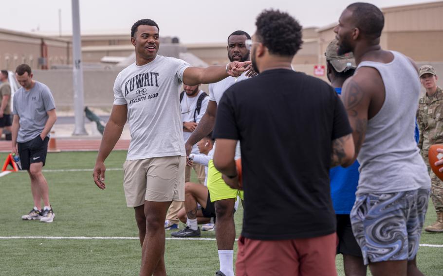 NFL players and airmen participate in a football drill