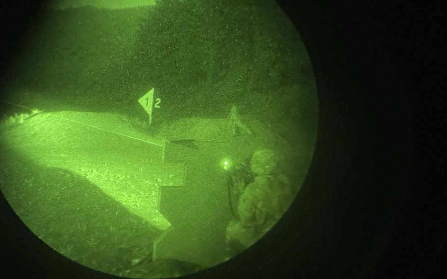 A soldier aims a weapon in this picture taken through a night vision lens.