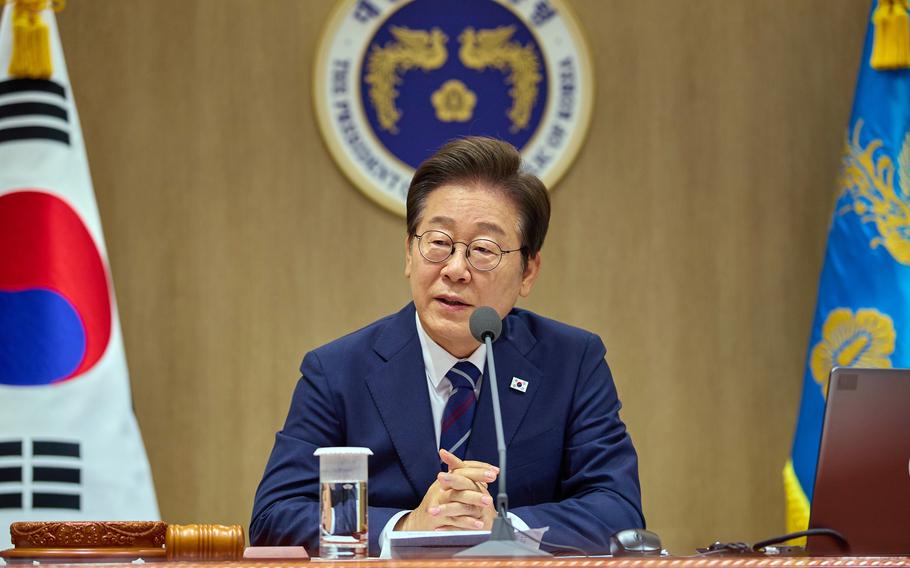 A South Korean government official in a dark blue suit and glasses speaks at a podium with a microphone during what appears to be an official press conference or meeting. 