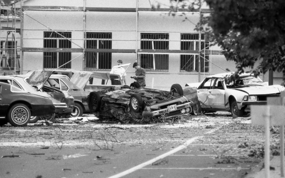 Investigators sift through rubble and wrecked automobiles following a car-bomb explosion in a parking lot at Rhein-Main Air Base.
