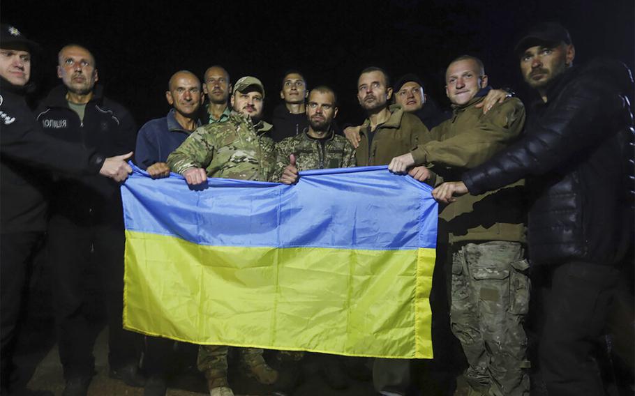 Ukrainian soldiers released in a prisoner exchange between Russia and Ukraine, hold the Ukrainian flag close to Chernihiv, Ukraine, late Wednesday, Sept. 21, 2022.