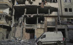 A Palestinian boy walks past a heavily damaged building.