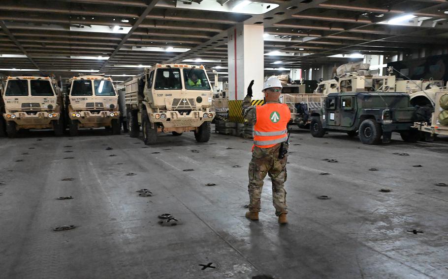 A soldier stands in front of military vehicles.