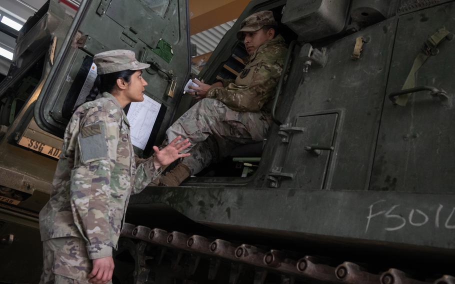 Capt. Kamalpreet Gill, commander of Charlie Battery, 1st Battalion, 77th Field Artillery Regiment, left, speaks with Spc. Juan Daza of Beta Battery at the unit’s motor pool in Grafenwoehr, Germany, Feb. 2, 2024. Gill’s battery, along with Charlie Battery, 1st Battalion, 6th Field Artillery Regiment, were reactivated in January. 