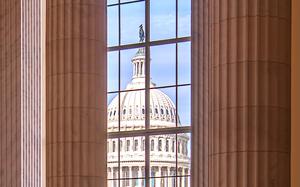 The U.S. Capitol dome seen through a window of another building.