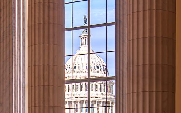 The U.S. Capitol dome seen through a window of another building.
