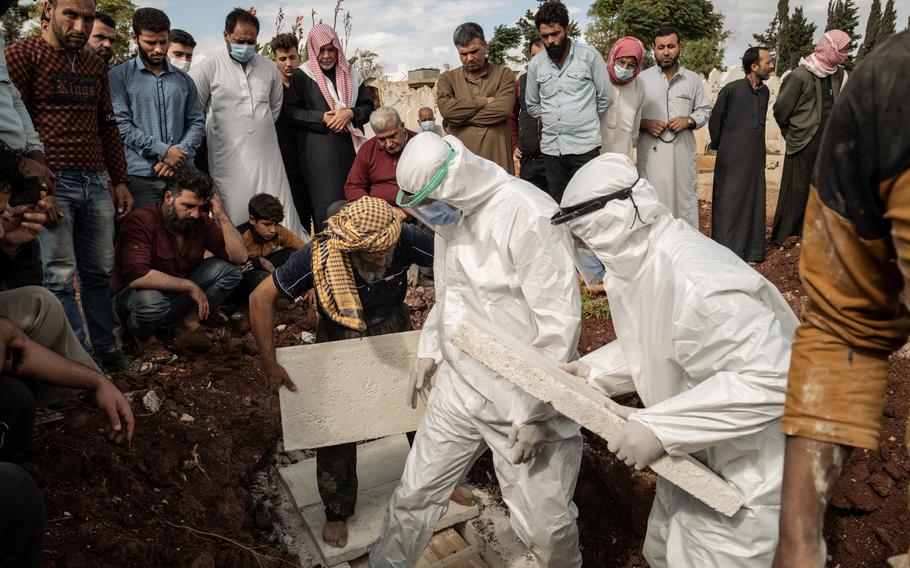 An undertaker and volunteers from Syria Civil Defense, or the White Helmets, bury Saleh Mohammed al-Kanash's body. 